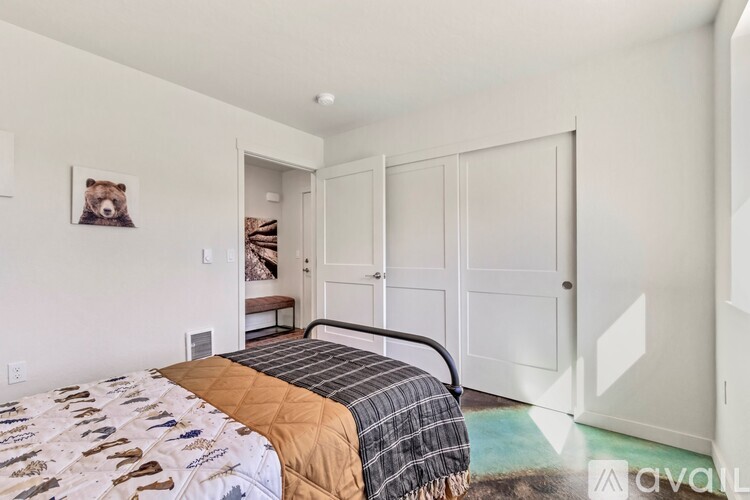 A bedroom with a bed covered in a quilt and a bear picture on the wall.