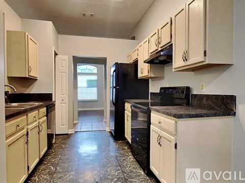 A kitchen with black appliances and marble countertops.