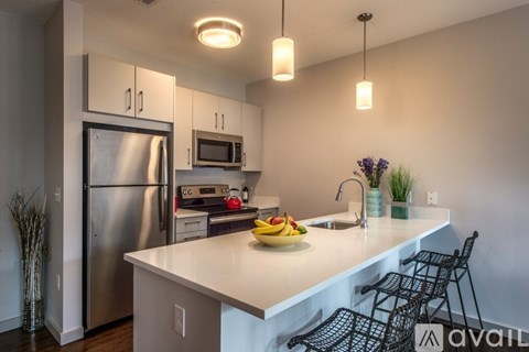 A kitchen with a refrigerator, microwave, and sink.