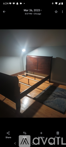 A room with a bed and a chair is shown in a dimly lit setting.