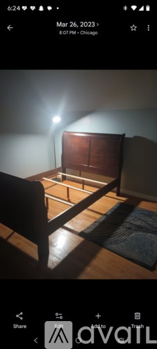 A room with a bed and a chair is shown in a dimly lit setting.
