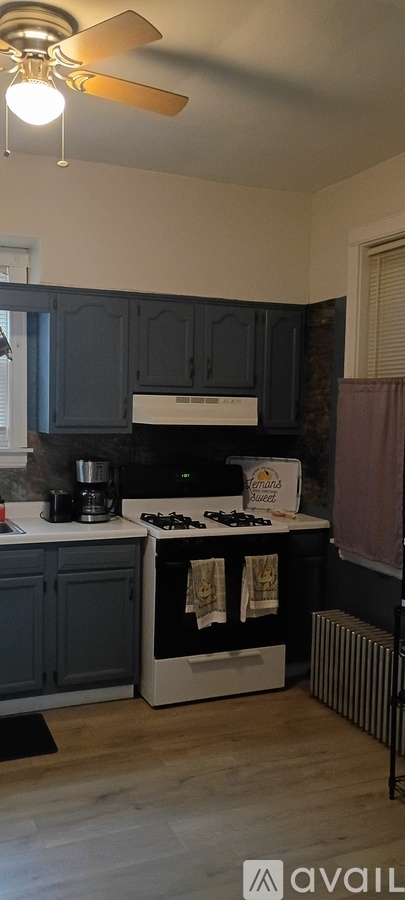 A kitchen with a white stove top oven and dark blue cabinets.