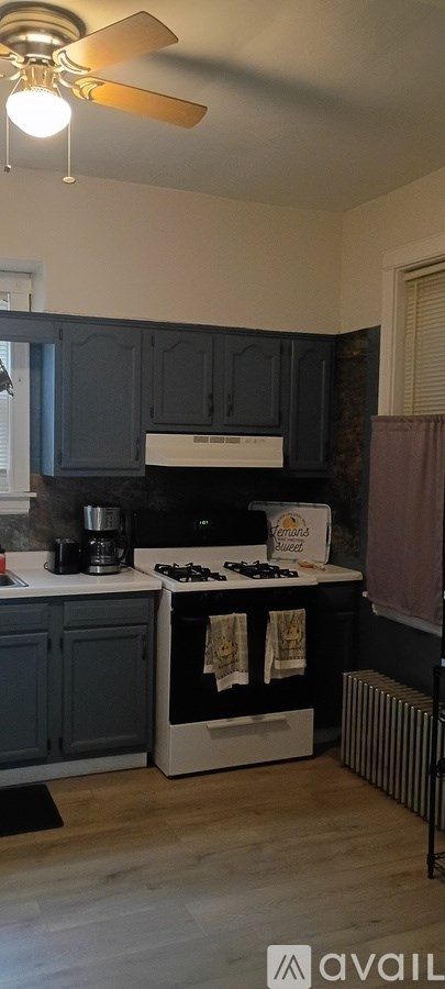 A kitchen with a white stove top oven and dark blue cabinets.
