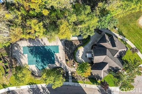 An aerial view of a house with a swimming pool surrounded by trees.