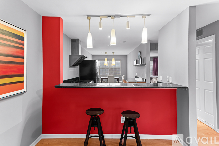 A kitchen with a red counter and bar stools.
