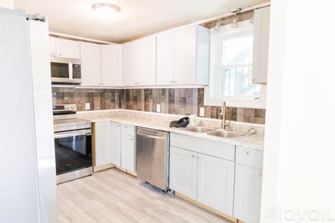 A kitchen with white cabinets and a wooden backsplash.