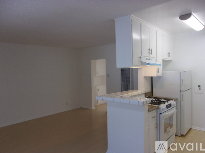 A kitchen with white cabinets and appliances in a room with white walls.