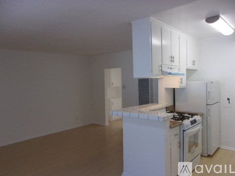 A kitchen with white cabinets and appliances in a room with white walls.