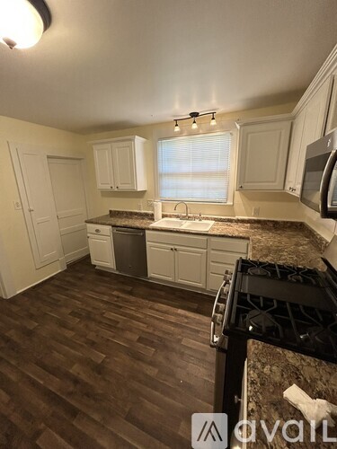 A kitchen with white cabinets and a black stove top.