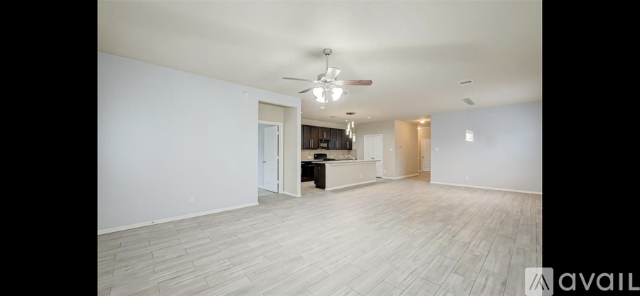 A spacious room with a kitchen area in the background.