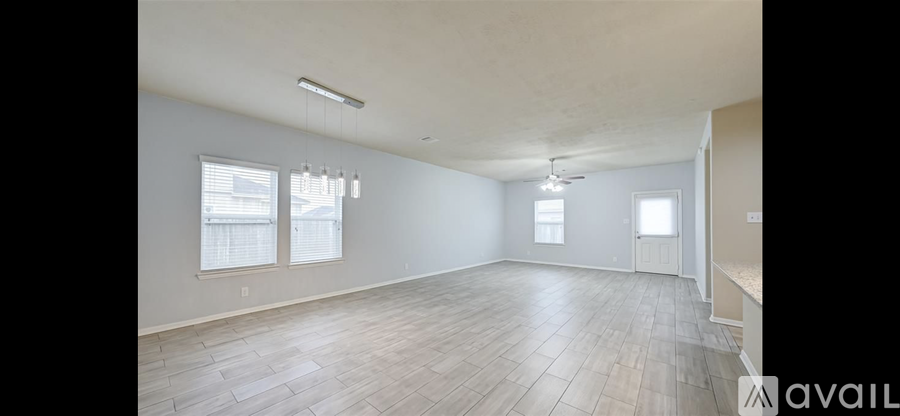 A spacious empty room with wooden flooring and white walls.