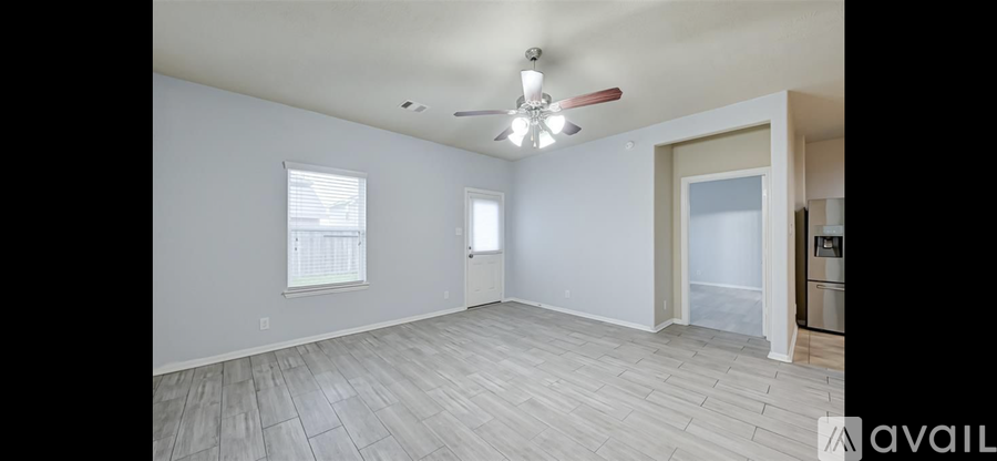 A spacious room with a ceiling fan and lighting fixture, and a window with blinds.