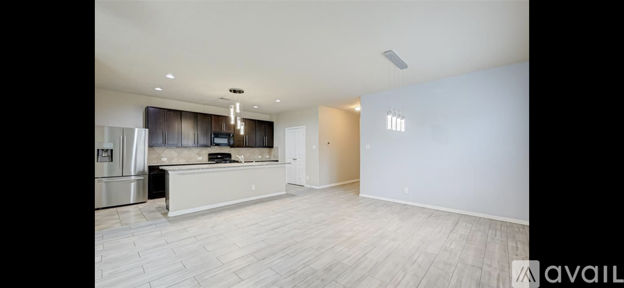 A spacious kitchen with a bar counter and a refrigerator.