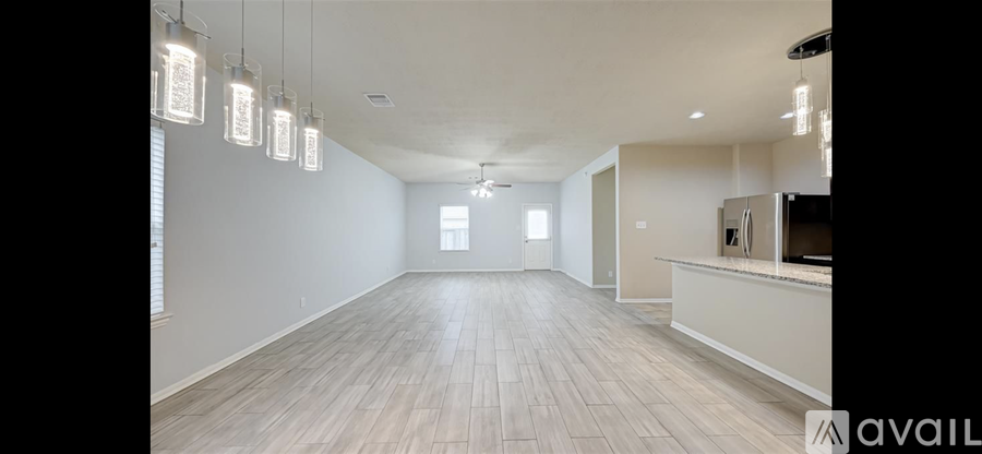 A spacious room with wooden flooring and a bar area.