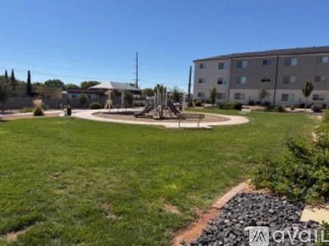 A playground with a slide and a building in the background.