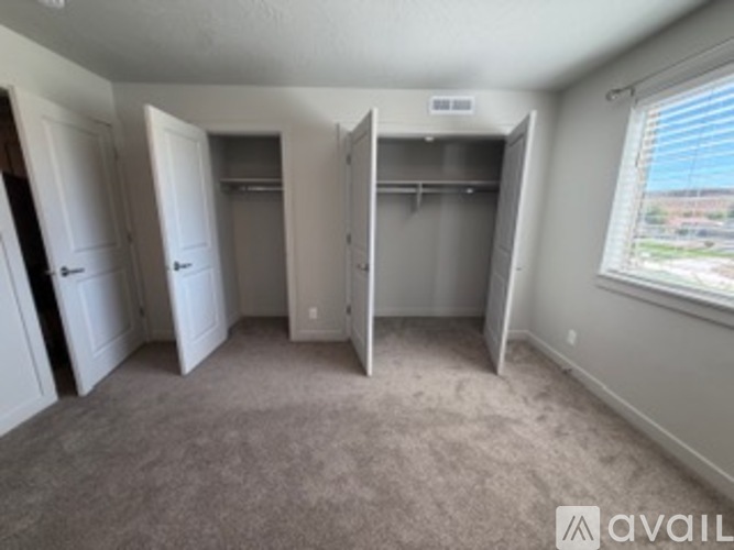 A room with a carpeted floor and a window with blinds.