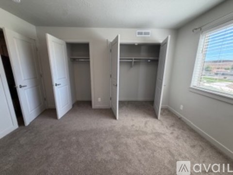 A room with a carpeted floor and a window with blinds.