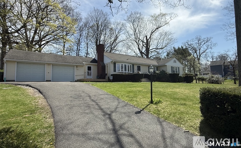 A house with a driveway and a sign in front of it.