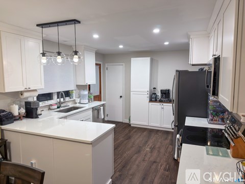 A kitchen with white cabinets and a black fridge.