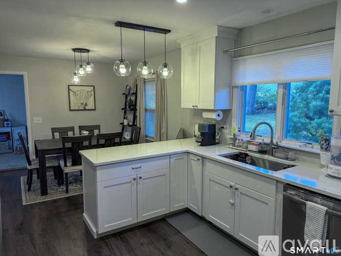 A kitchen with white cabinets and a wooden floor.
