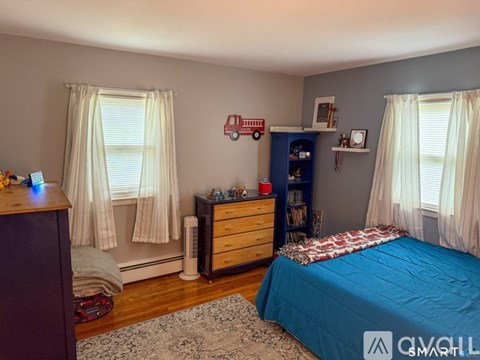 A bedroom with a blue bedspread and a white ceiling fan.