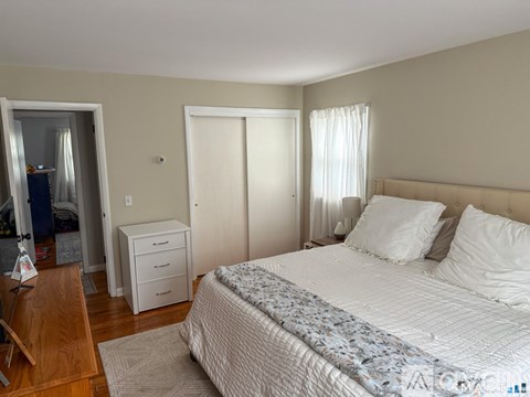 A bedroom with a large bed and a wooden dresser.