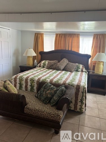A bedroom with a large bed and two lamps.