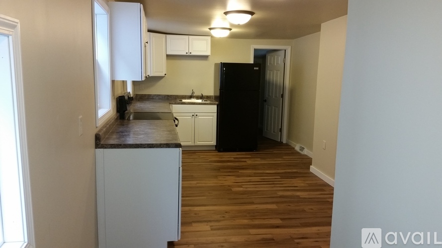 A kitchen with white cabinets and a black refrigerator.