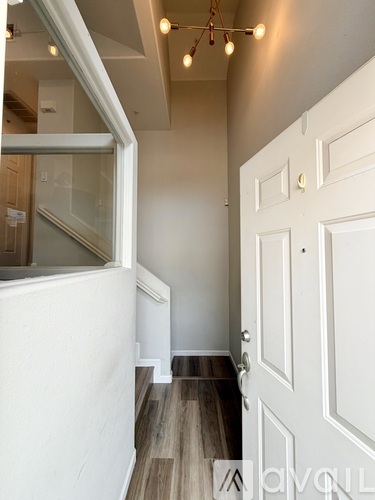 A hallway with a white door and a wooden floor.