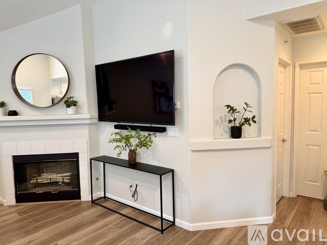 A black TV is mounted on a white wall above a black and white console table.