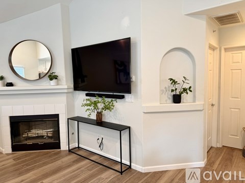 A black TV is mounted on a white wall above a black and white console table.