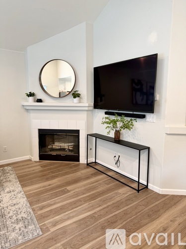 A living room with a fireplace, a mirror, a TV and a plant.