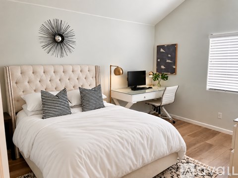 A bedroom with a large bed and a desk with a chair.