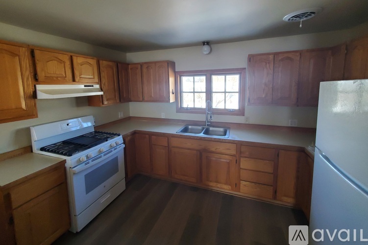 A kitchen with wooden cabinets and a white stove top oven.