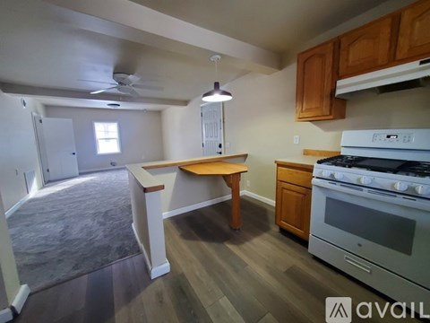 A kitchen with a white stove top oven and a wooden table.