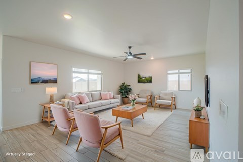 A living room with a white couch, pink chairs, and a painting on the wall.