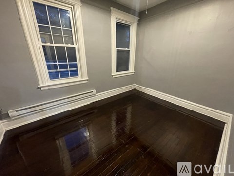 A room with wooden floors and two windows.