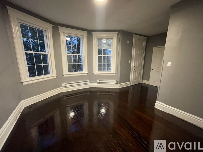 A room with a wooden floor and three windows.