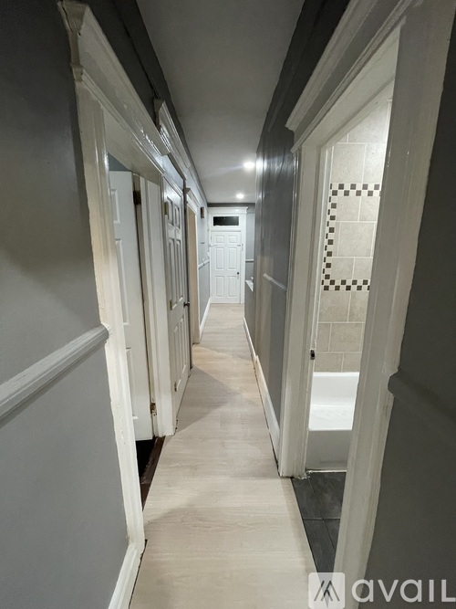 A long hallway with white doors on the left and a tiled wall on the right.