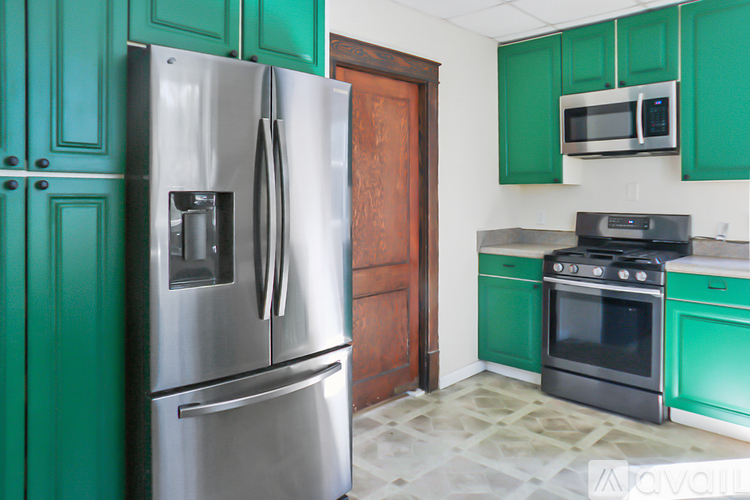 A kitchen with green cabinets and a stainless steel refrigerator.