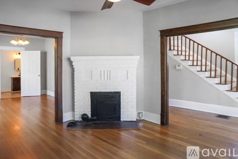 A living room with a fireplace and a staircase.