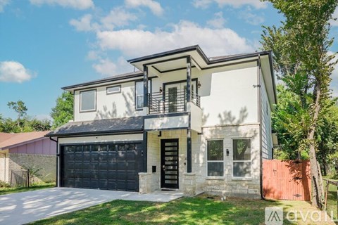 A modern two-story house with a balcony on the upper floor.