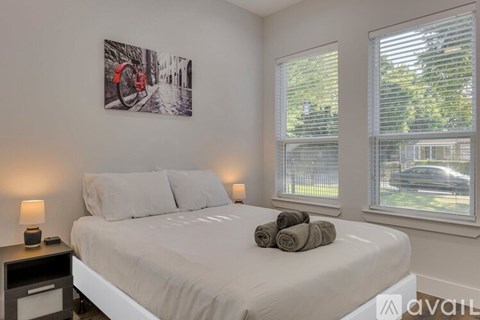 A bedroom with a large bed, a nightstand with a lamp, and a picture on the wall.