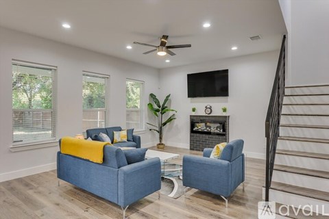 A living room with a blue couch, a yellow throw, and a television mounted on the wall.