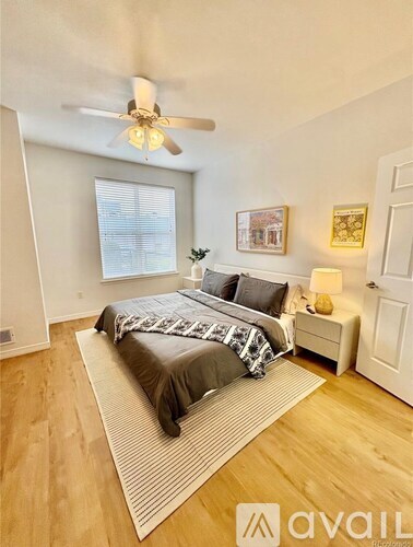 A bedroom with a bed, a ceiling fan, and a nightstand.