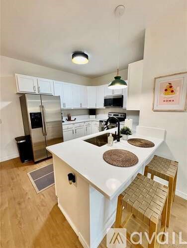 A kitchen with white cabinets and a white island with a brown mat on it.