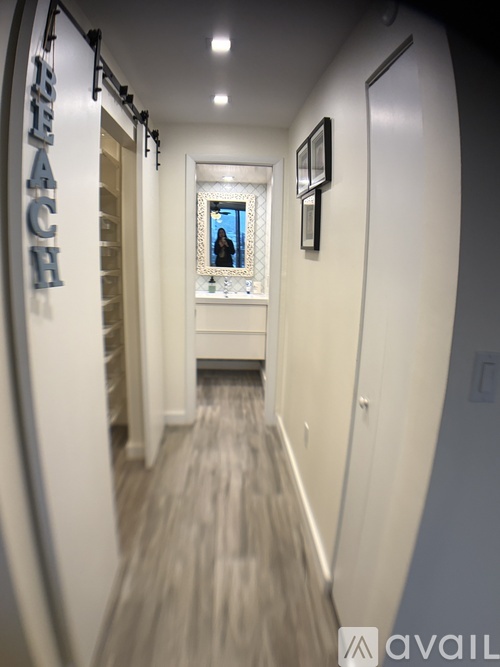 A hallway with a surfboard wall and a mirror on the wall.
