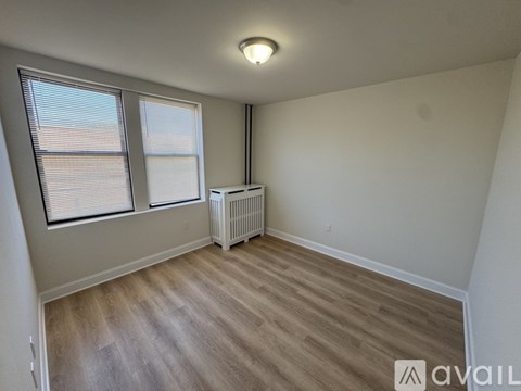 A room with a window, a radiator, and wooden flooring.