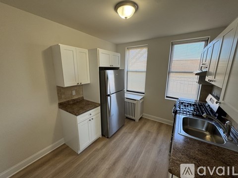 A kitchen with white cabinets and a black refrigerator.