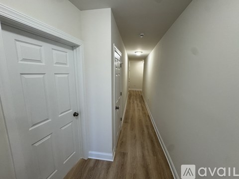 A long hallway with white walls and wood flooring.
